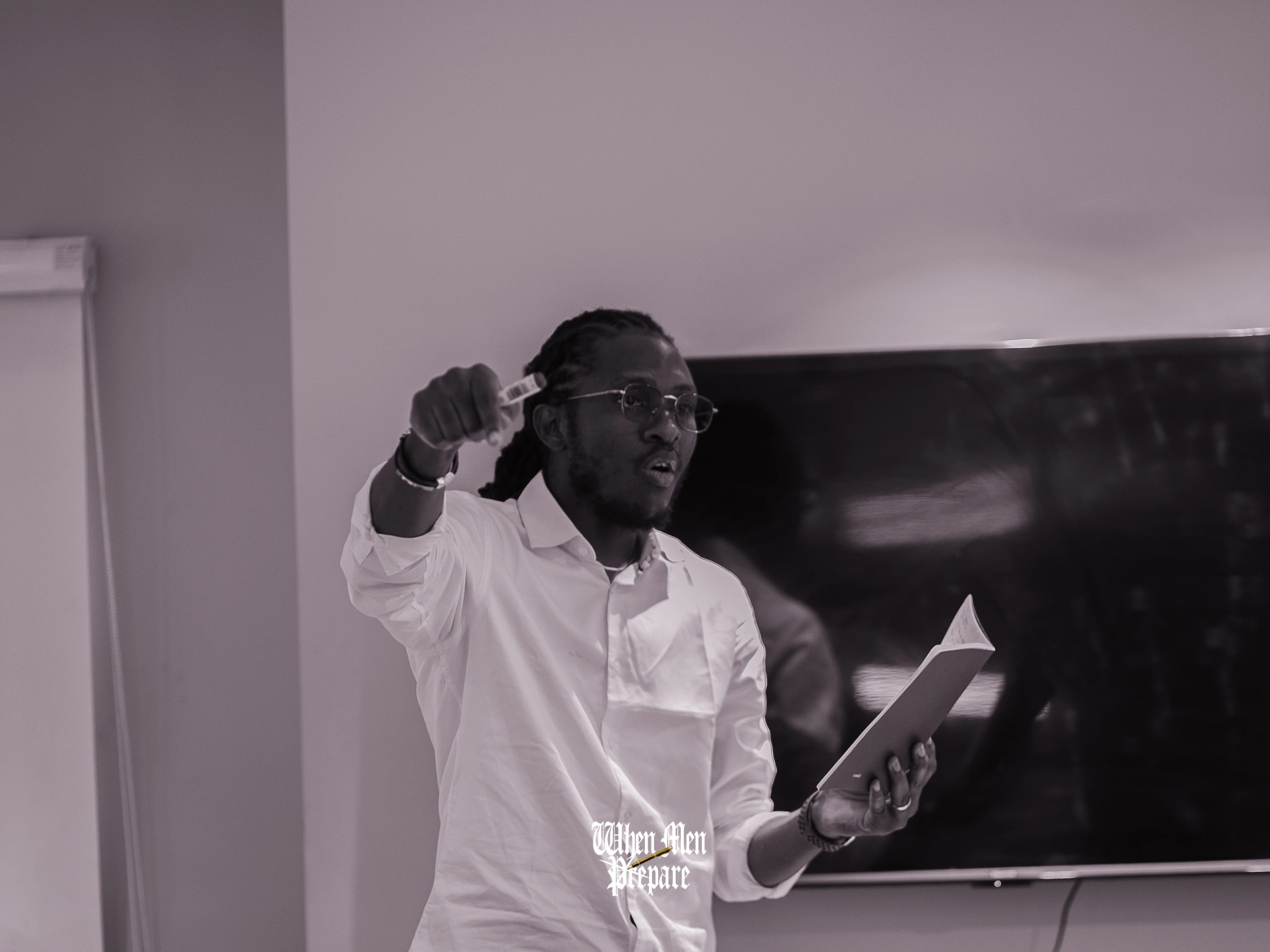A man in a white shirt making a point, notes in his other hand